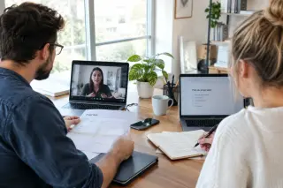 Deux professionnels collaborant à distance, assis chacun devant un ordinateur portable dans un bureau lumineux et moderne, échangeant via visioconférence et consultant des documents, ambiance sérieuse et productive.